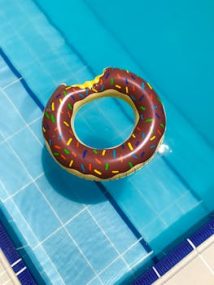 A vibrant donut-shaped float rests on a clear swimming pool. Perfect for summer vibes.